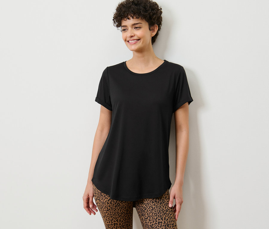 Nő pózol egy fekete hosszú felsőben.