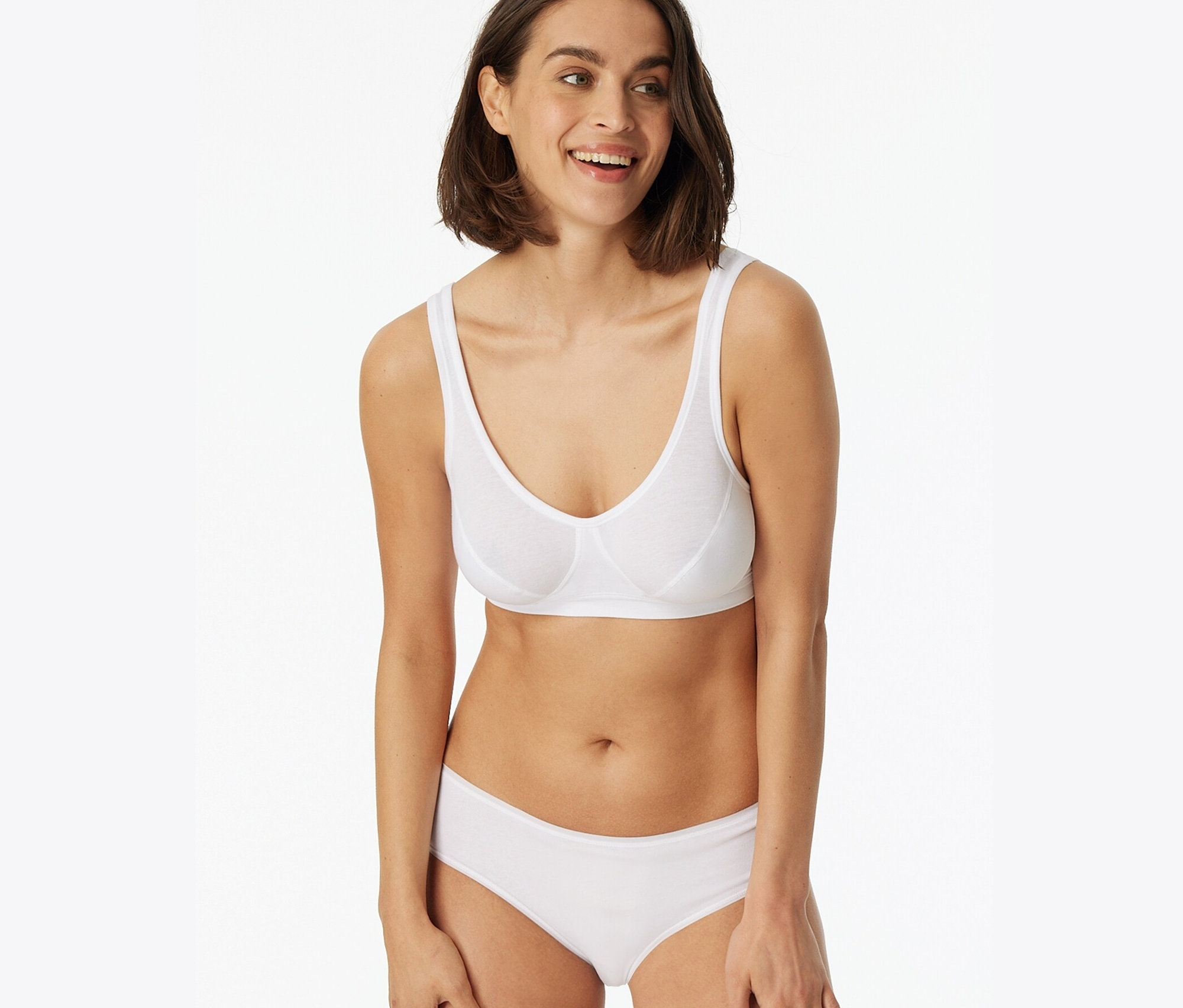 Mosolygó nő fehér melltartót és 2 SCHIESSER hipster alsót visel, fehér színben.