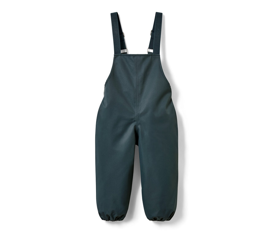 Kisgyerek kantáros esőnadrág, palakék háttér előtt.