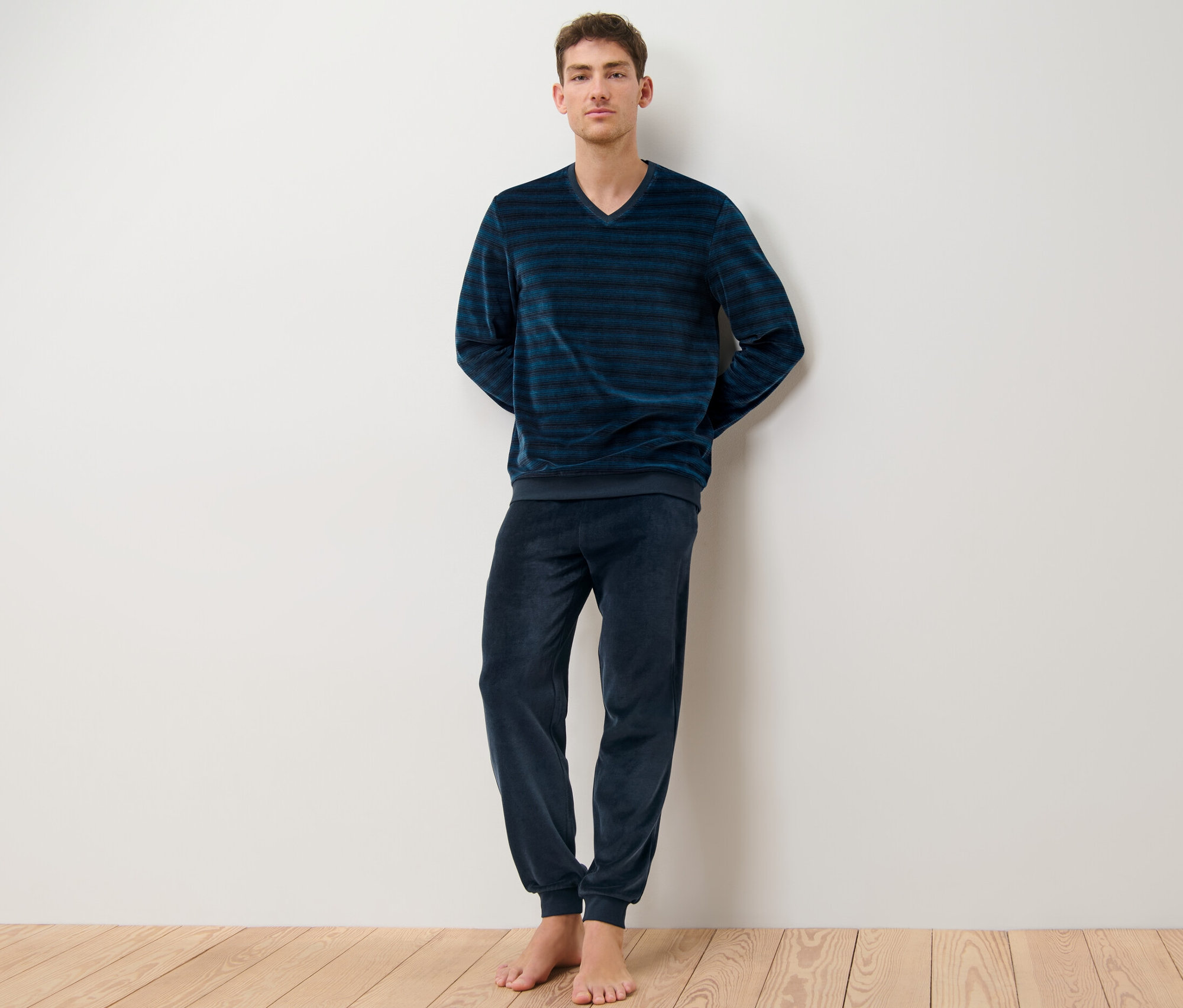 Egy férfi áll csíkos plüsspizsamában.