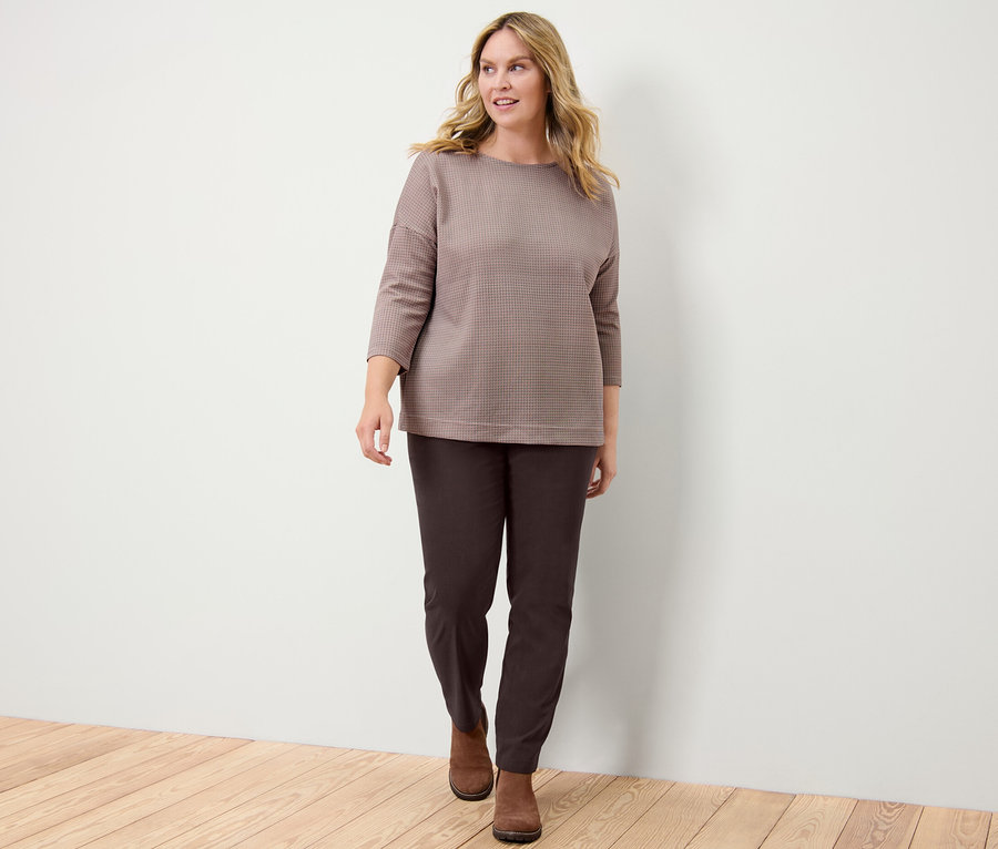 Nő kockás szabadidőfelsőben és női bengalin nadrágban.