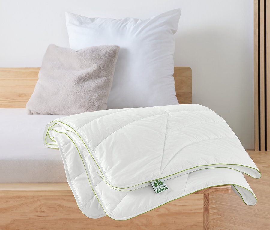 Egy fehér irisette® greenline steppelt paplan Outlast®-technológiával egy ágyon.