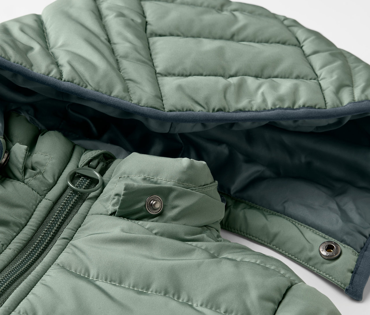 Egy zöld, steppelt gyerekkabát részlete.