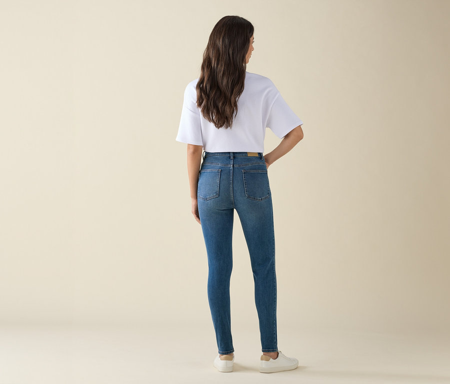 Hátulnézet egy barna hajú nőről kék farmerben és fehér pólóban.