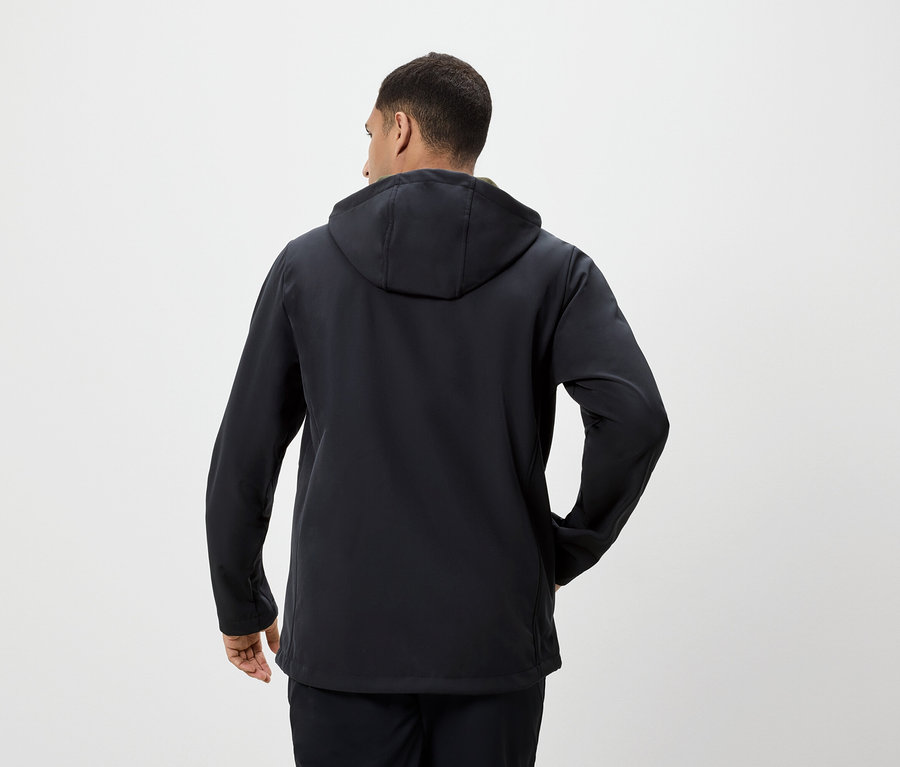 Egy férfi háttal a kamerának fekete kapucnis kabátot visel.