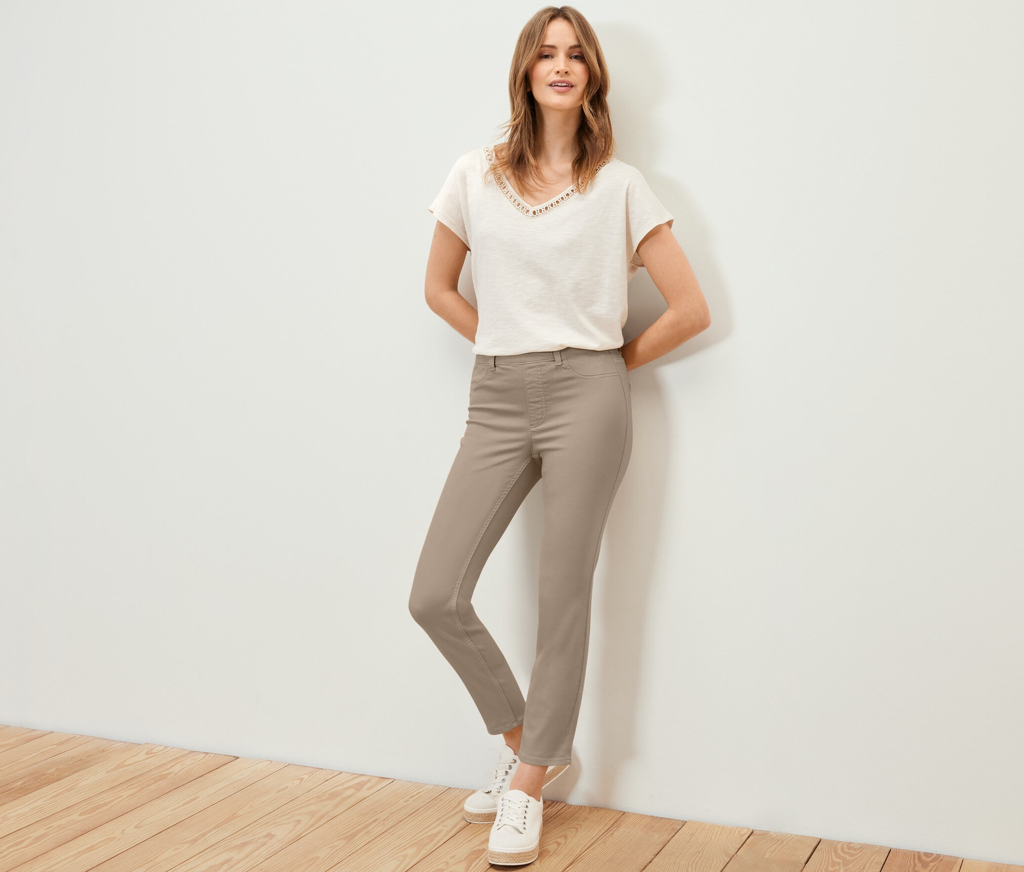 Nő pózol 7/8-os treggingsben, pólóban és tornacipőben.