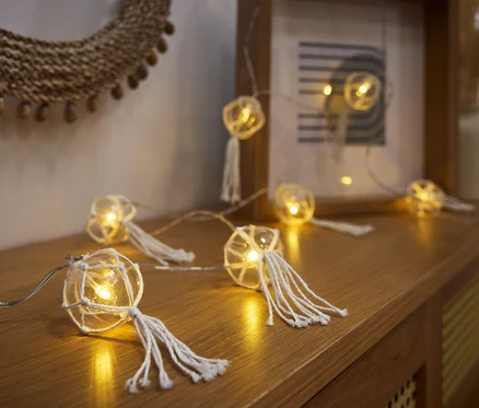 LED-Kugel-Lichterkette fekszik egy fa komódon.