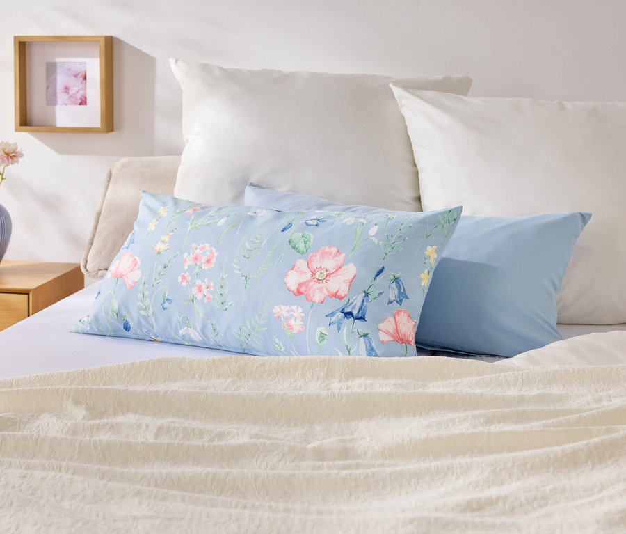 Egy ágyon különböző színű és mintázatú párnák vannak.