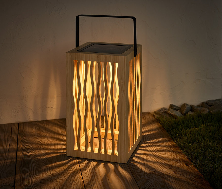 Egy napelemes viharlámpa áll egy fa padlón, árnyékot vetve.