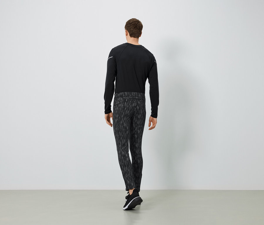 Egy férfi fekete hosszú ujjúban és mintás nadrágban, hátulnézetből.