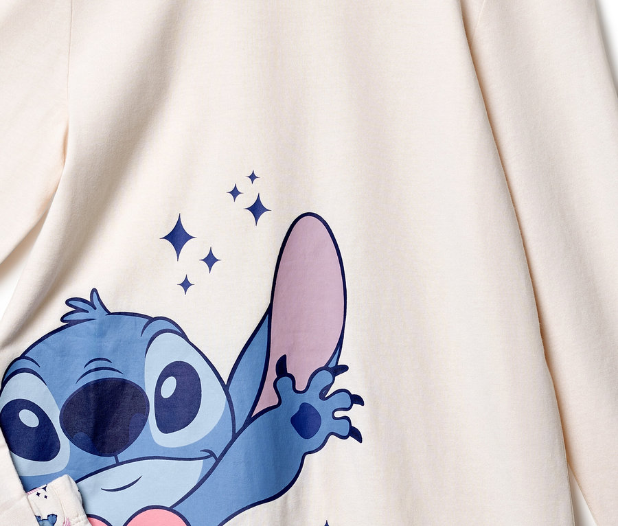 Krémszínű felső részletgazdag nézete kék Stitch nyomtatással és csillogó csillagokkal.