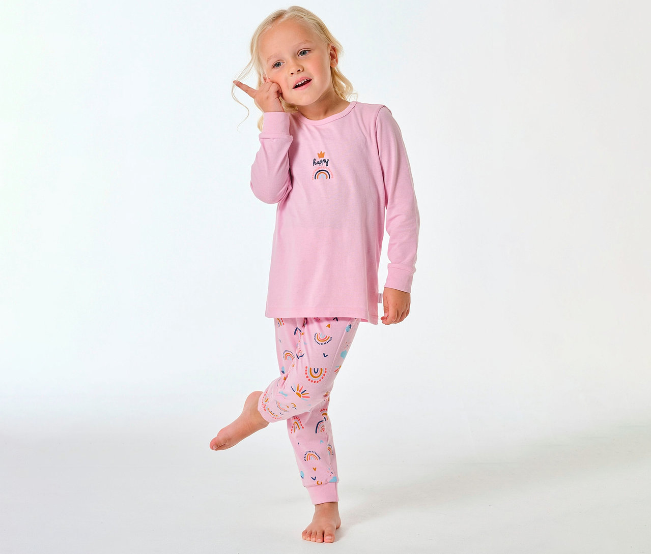 Lány SCHIESSER hosszú gyerekpizsamában, szivárványmintával a nadrágon és a felsőn.