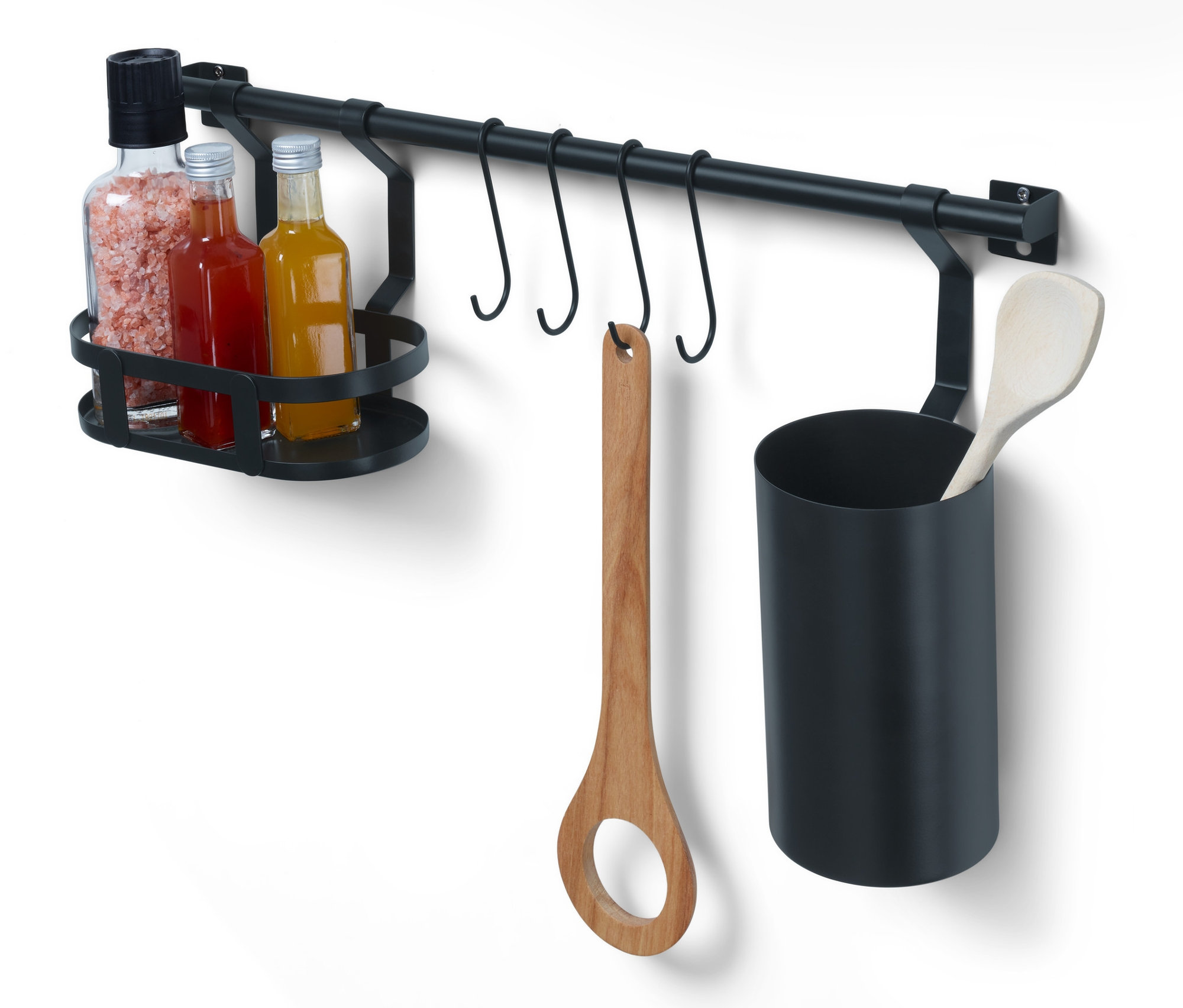 Egy konyhai fali sín, eszköztartóval látható egy fehér falon. A sínen konyhai eszközök, fűszerek és olajos üvegek lógnak.