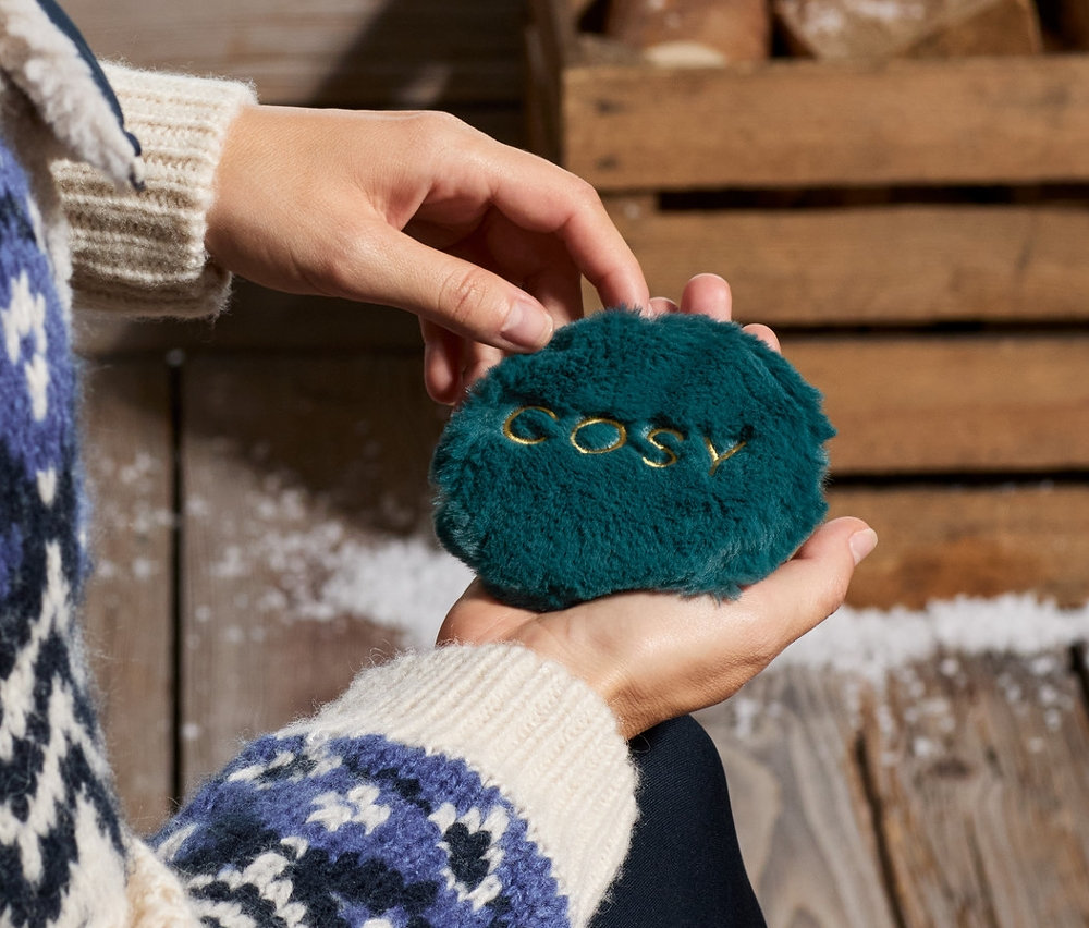 Egy nő 2 zsebmelegítő párnát tart a kezében.