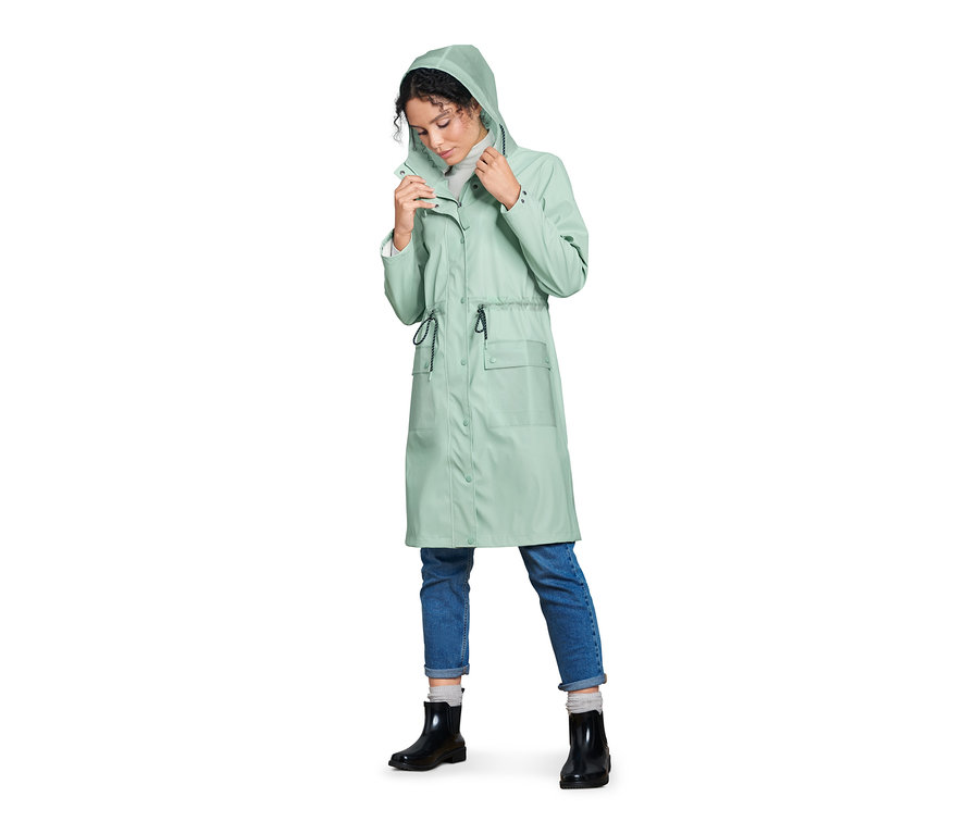Nő igazítja a kapucnit a menta színű női parka esőkabátján.