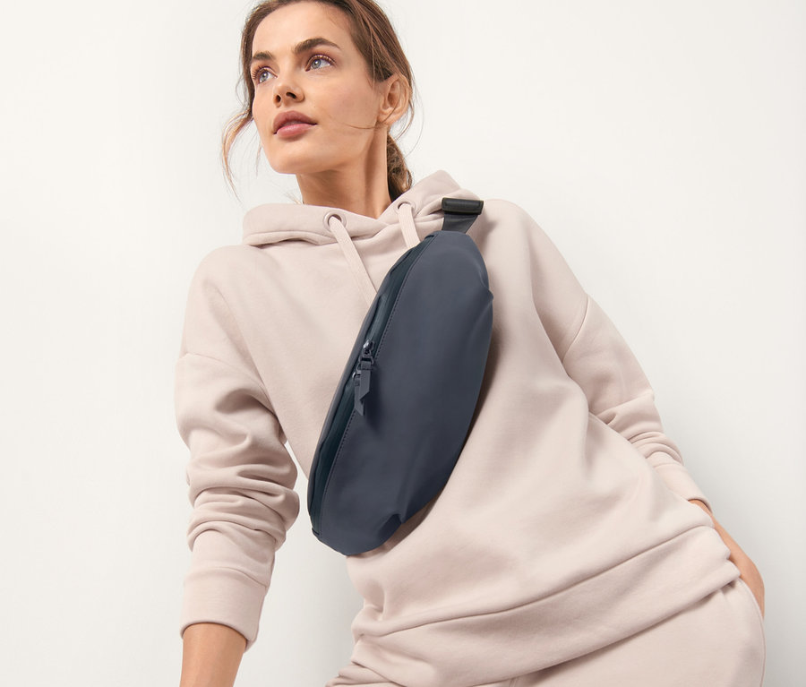 Nő pózol sötétkék övtáskával a mellkasán.