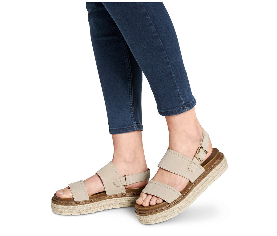 Farmerben lévő lábakon bézs színű női bőr szandál.