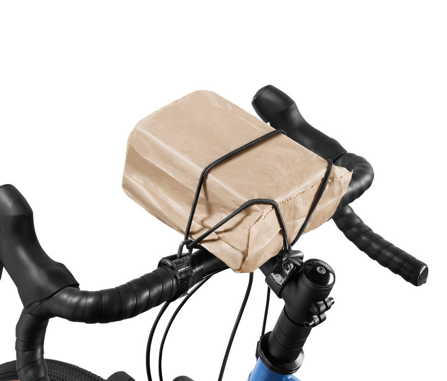 Barna papírzacskó rögzítve a kormányra kerékpáros csomagrögzítő pánttal.