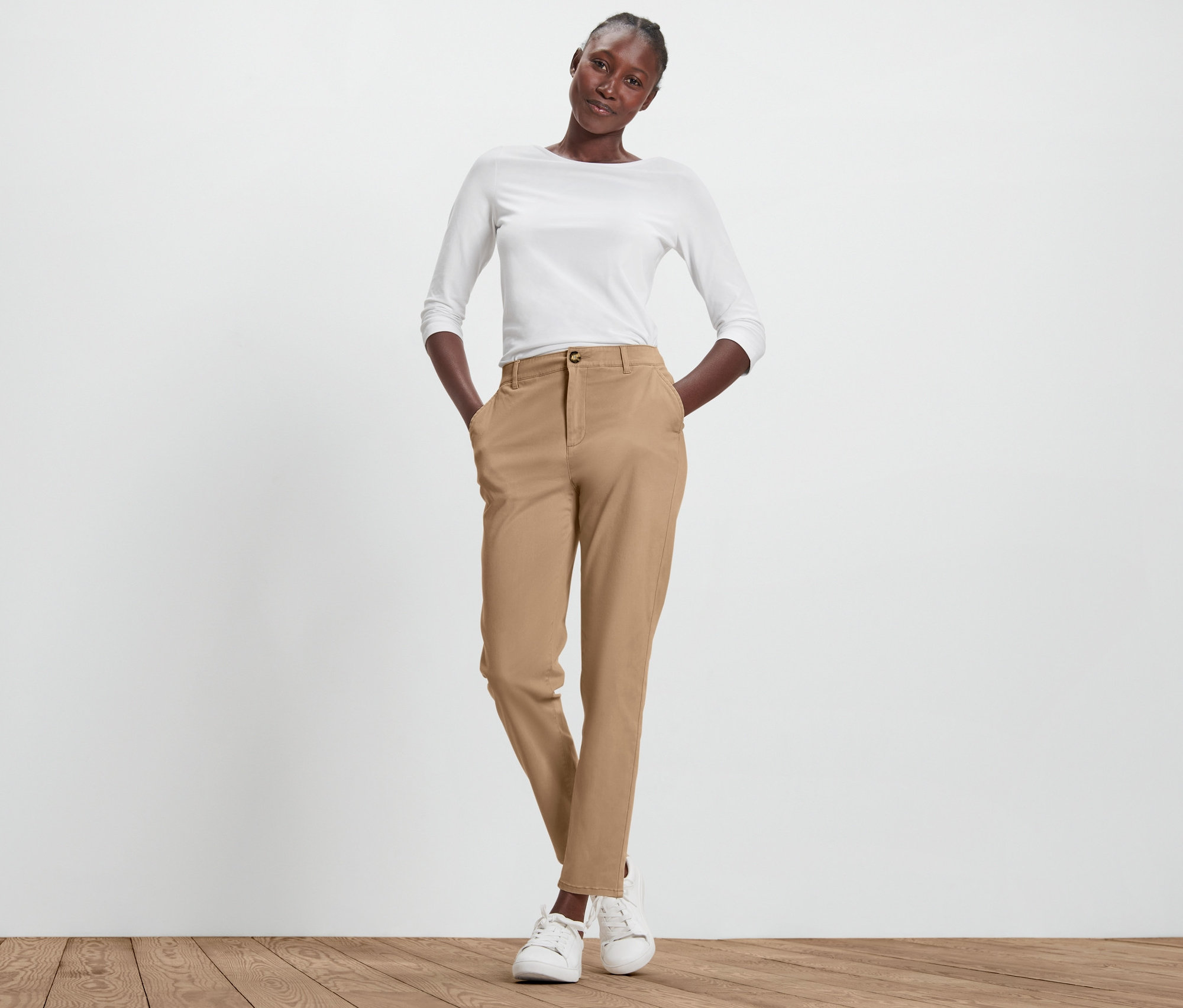 Nő pózol bézs chino nadrágban.
