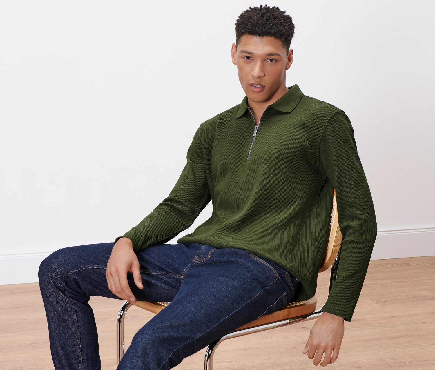 Férfi ül a széken, khaki színű, hosszú ujjú pólóing van rajta.