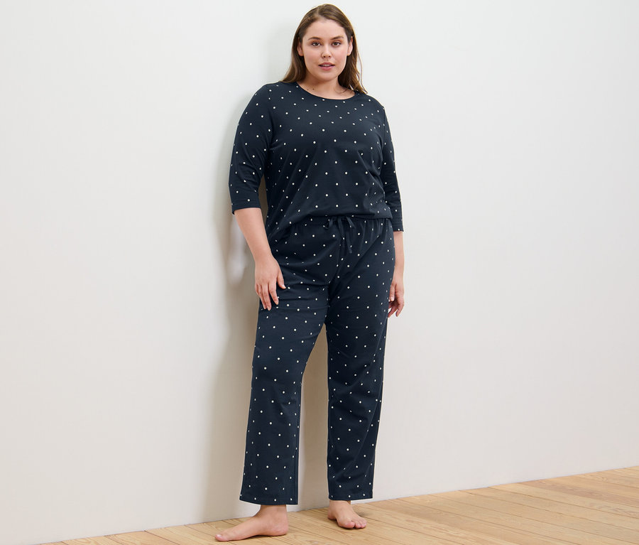Egy nő áll pöttyös pizsamában.