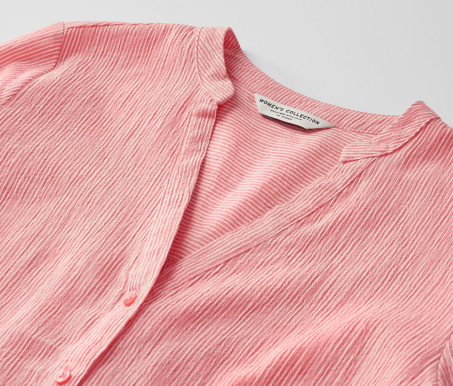 Egy korall színű, csíkos hosszú tunika részlete.