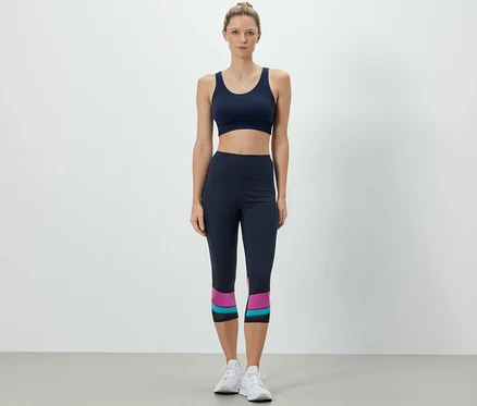 Nő sportmelltartót és 3/4-es sportnadrágot visel.