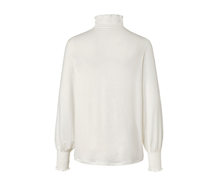Egy krémszínű, állógalléros ingblúz részlete.
