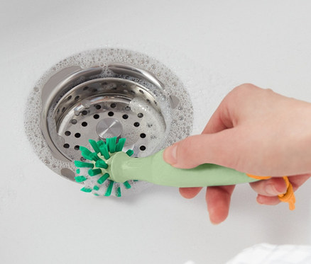 Nő tisztítja a mosogatót univerzális tisztítókefével.