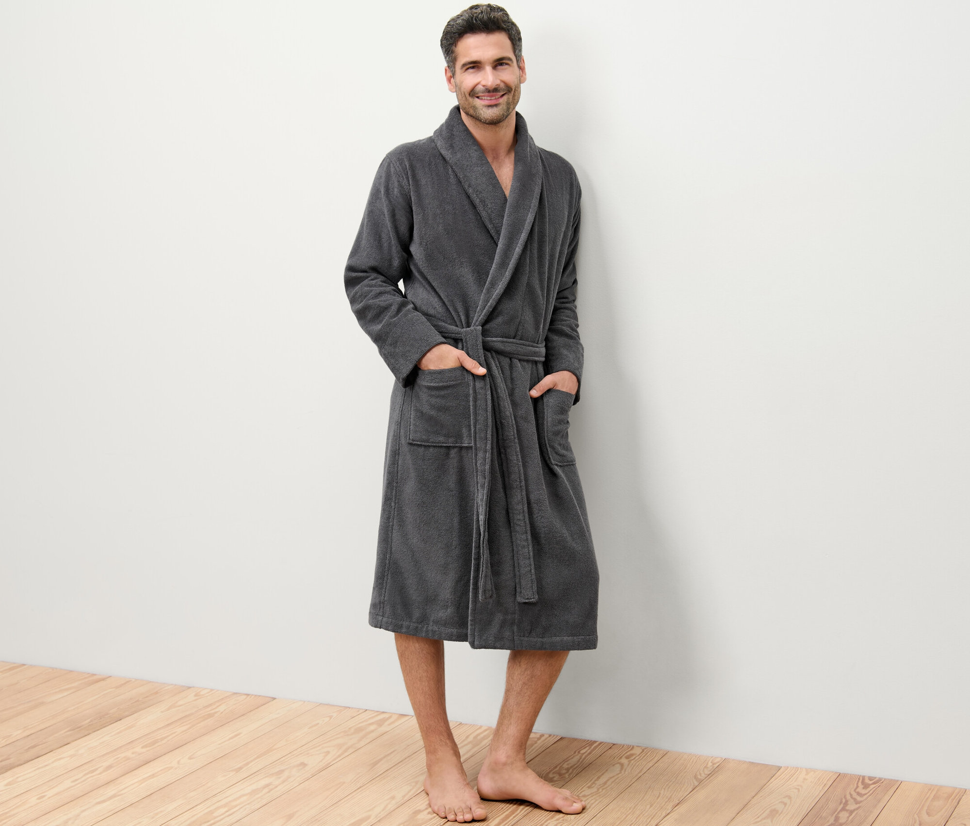 Egy férfi áll, és egy szürke férfi fürdőköpenyt visel.