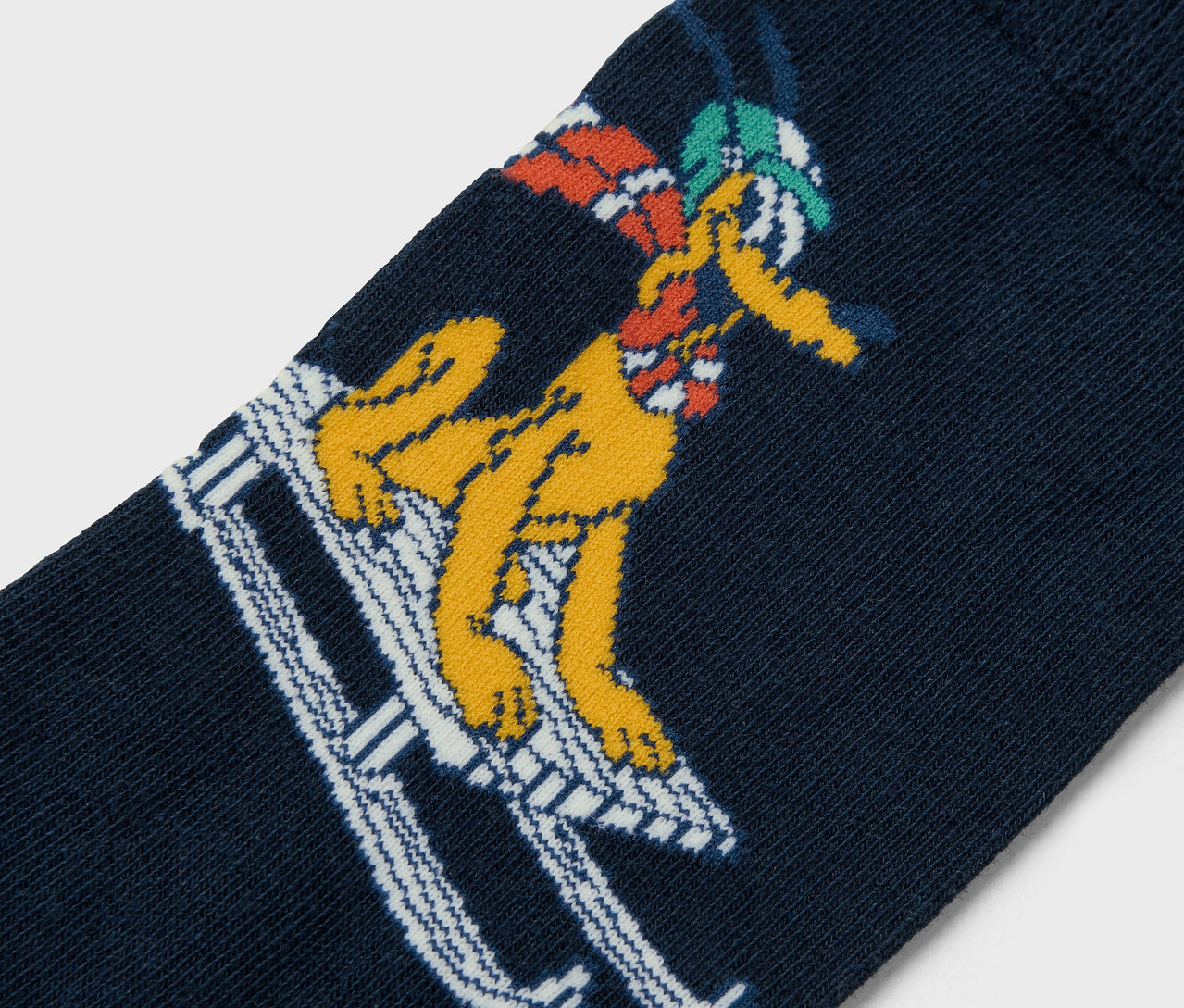 Egy sötétkék zokni közelképe, amelyen egy sárga rajzfilmfigura síel.