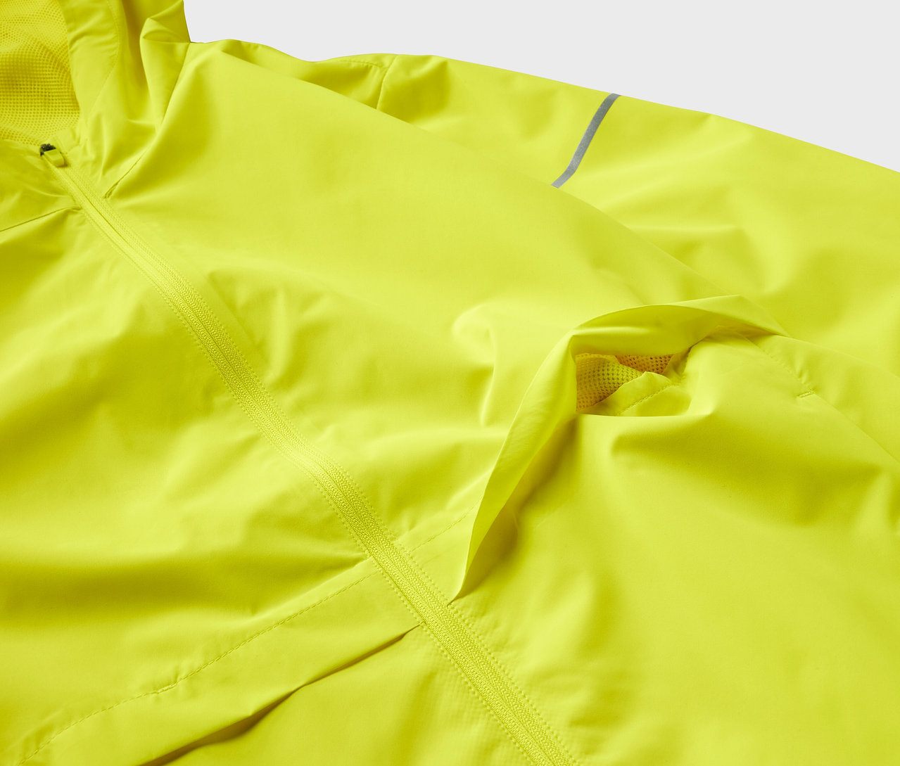 Egy sárga, texturált dzseki részlete cipzárral.