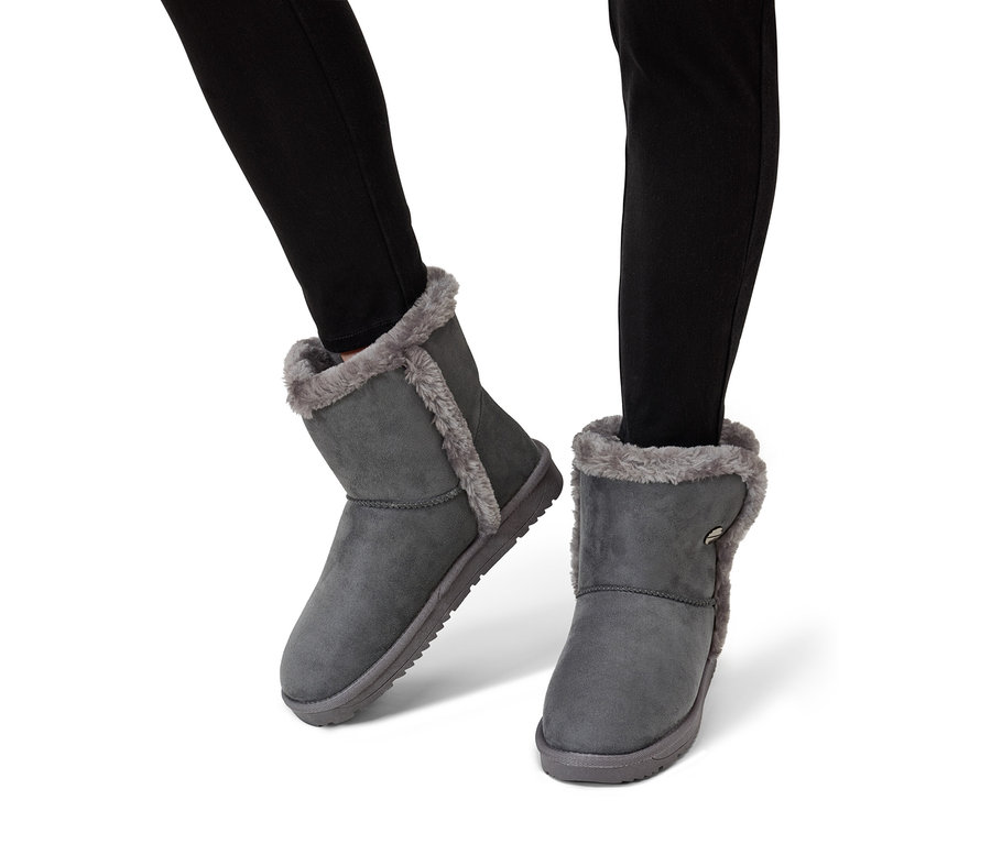 Fekete farmernadrágot viselő lábak szürke, szőrmebélésű bokacsizmában.