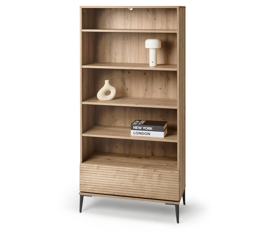 A képen egy lamellás hatású »REET« polc látható, melynek polcain olyan dekorációs tárgyak találhatók, mint egy lámpa, egy váza és könyvek.