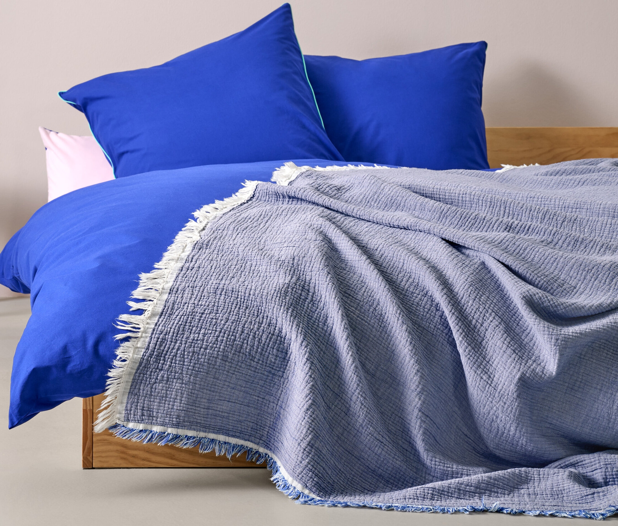 Egy ágyon egy kék muszlin ágytakaró (220 x 240 cm) látható.