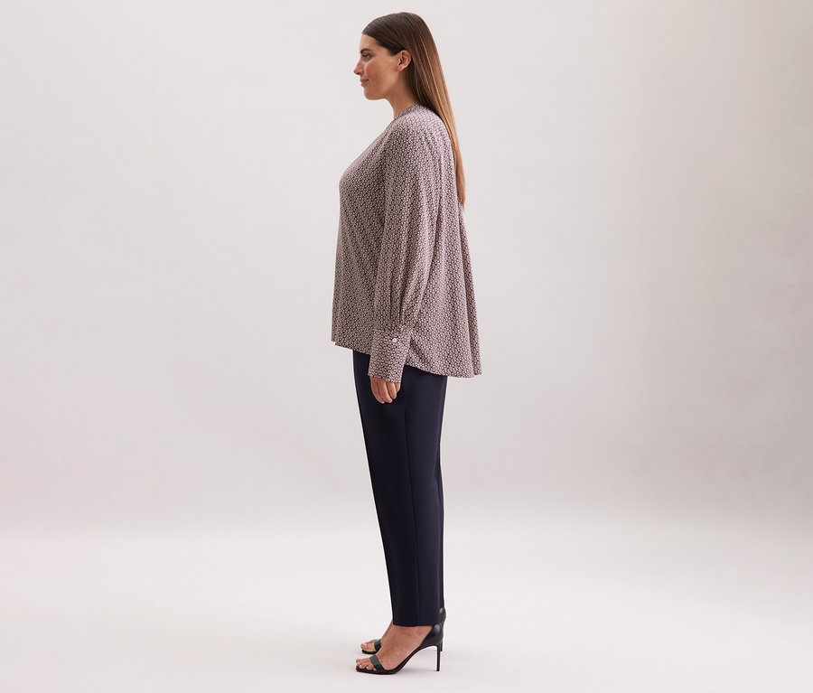 Nő visel egy ekrü-bordó mintás Seidensticker viszkóz tunikát, sötét nadrággal és fekete magassarkúval kombinálva.
