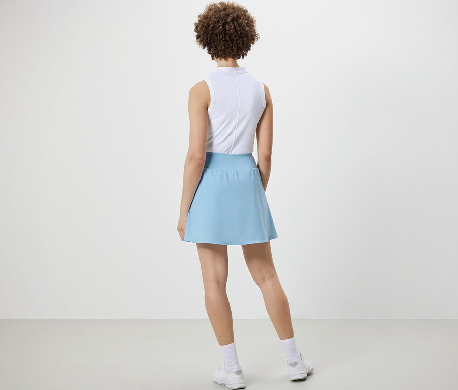 Háttal álló nő világoskék sportszoknyában.