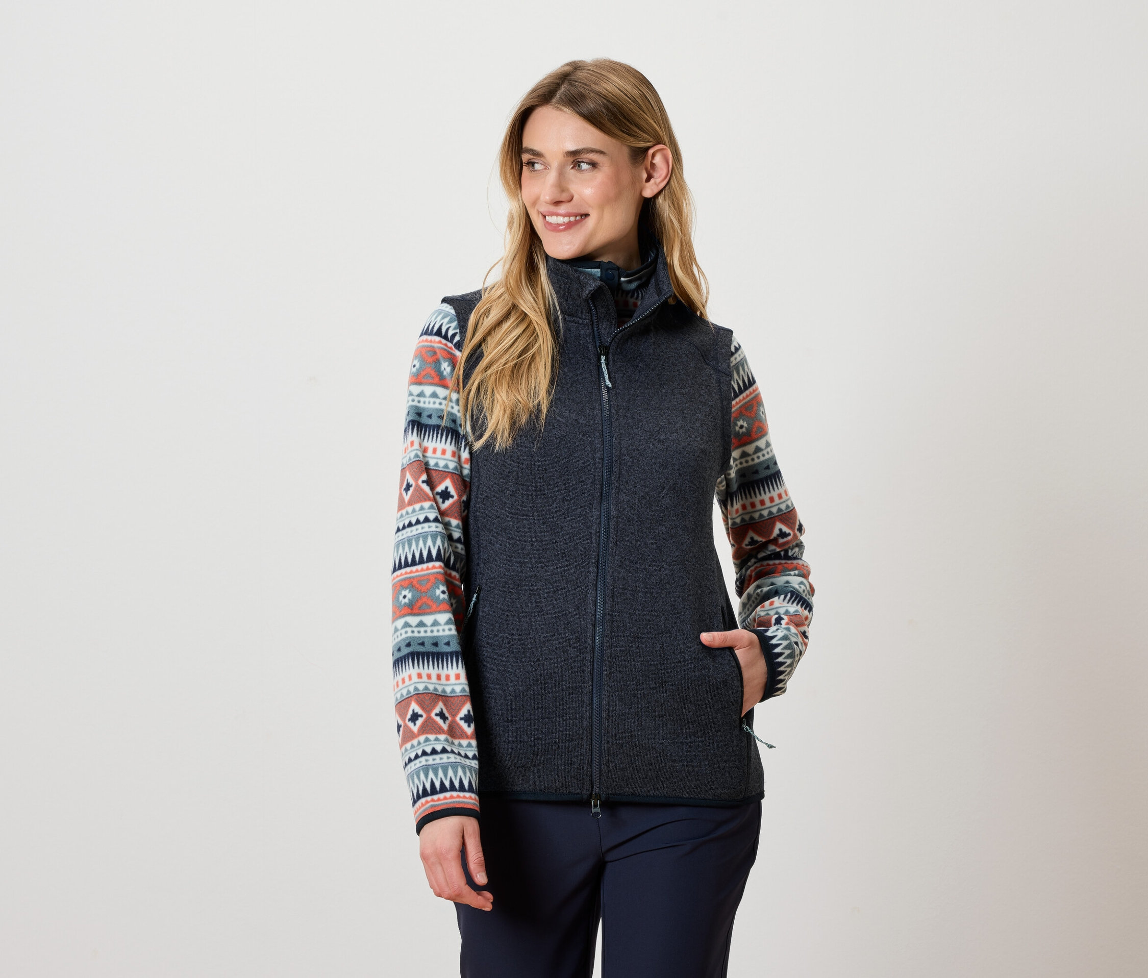 Nő visel sötétszürke mellényt és mintás felsőt.