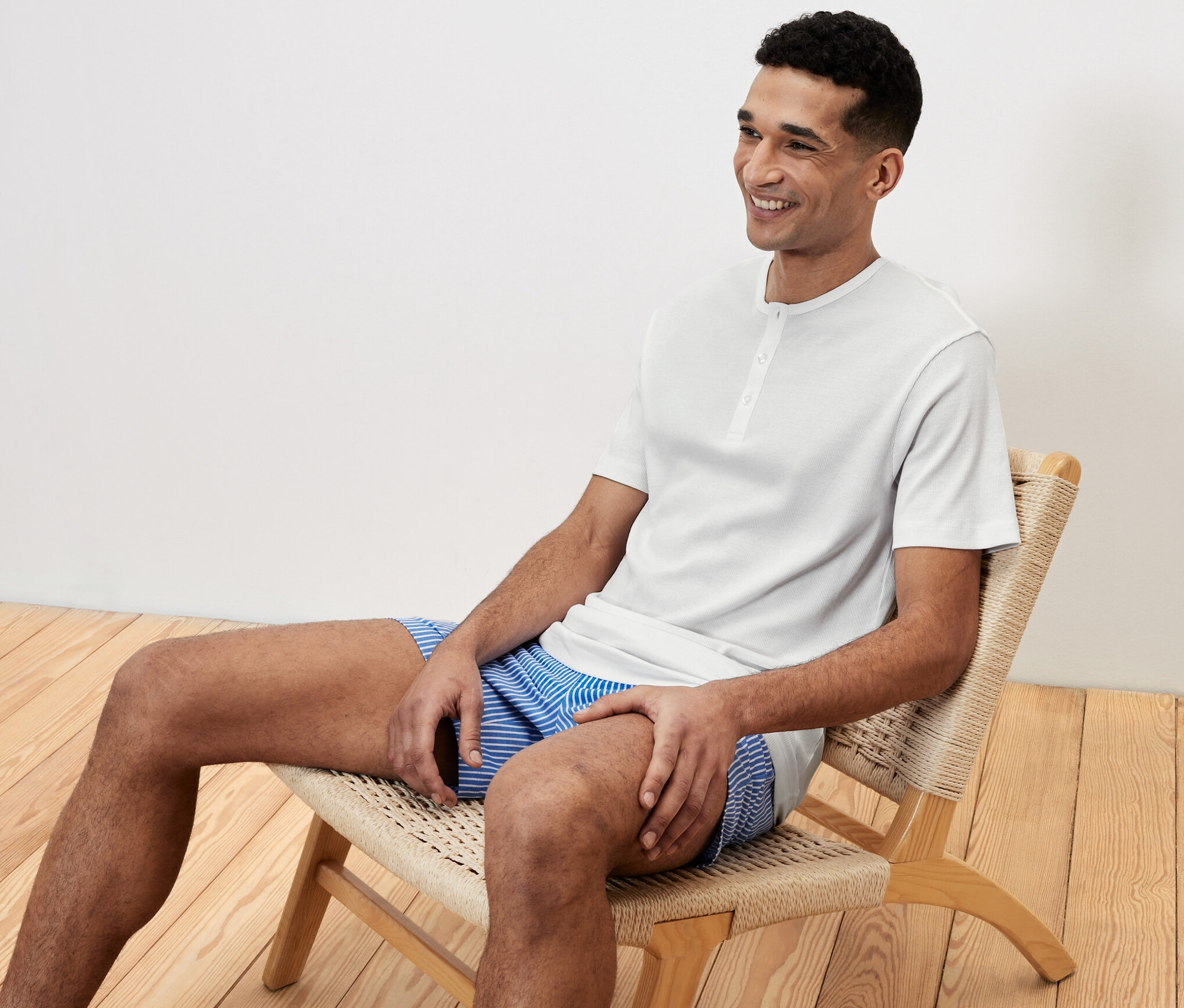 Férfi ül egy széken rövidnadrágos pizsamában és mosolyog.