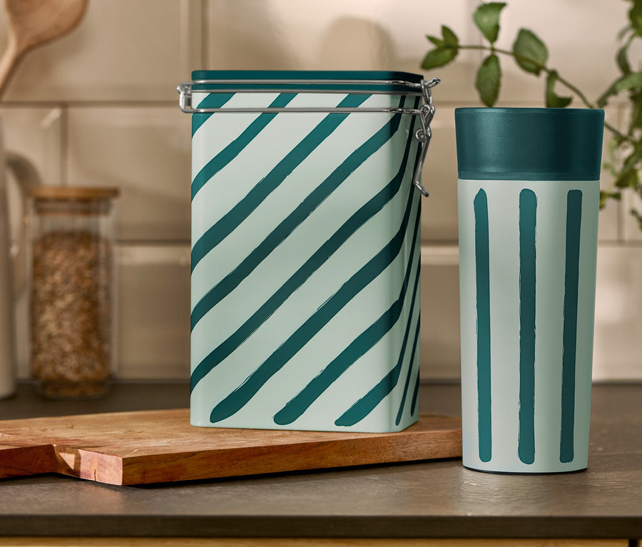 Csíkos kávétartó doboz és Coffee-to-go bögre áll egy konyhaasztalon.