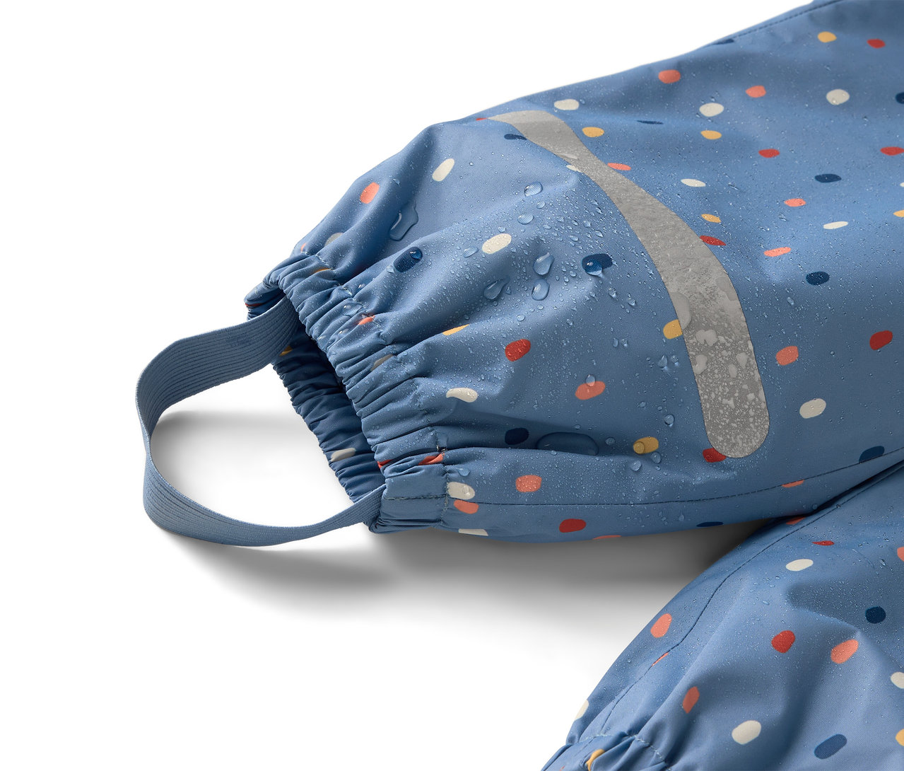 Egy kék, színes pöttyös esőruha közeli képe fényvisszaverő csíkkal, amin vízcseppek láthatók.