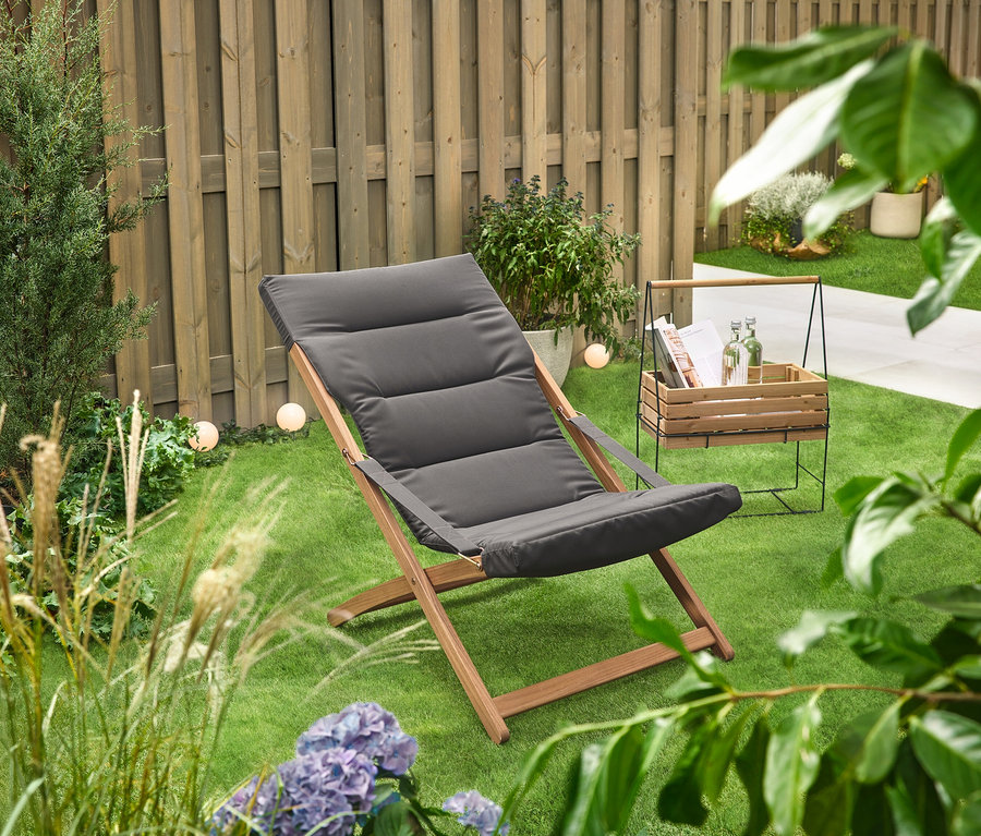 A zöld gyepen egy »Elin« gyógynövénytartó láda áll egy nyugágy mellett.