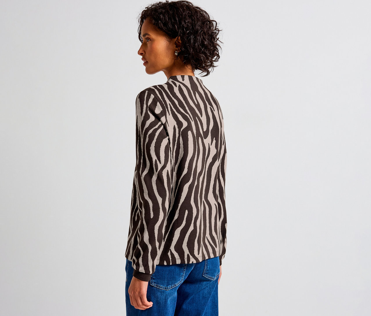 Nő visel egy zebra mintás Street One jacquard pólót és kék farmert.