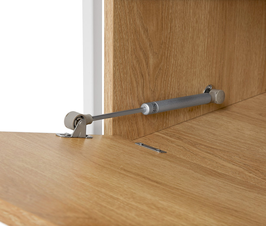 Egy világosbarna fa felületen lévő bútorsarok részletes képe.