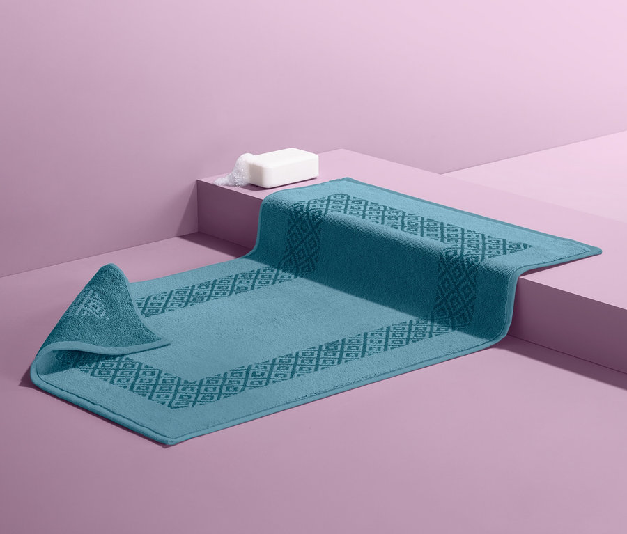 Kék fürdőszoba szőnyeg lila háttérrel.