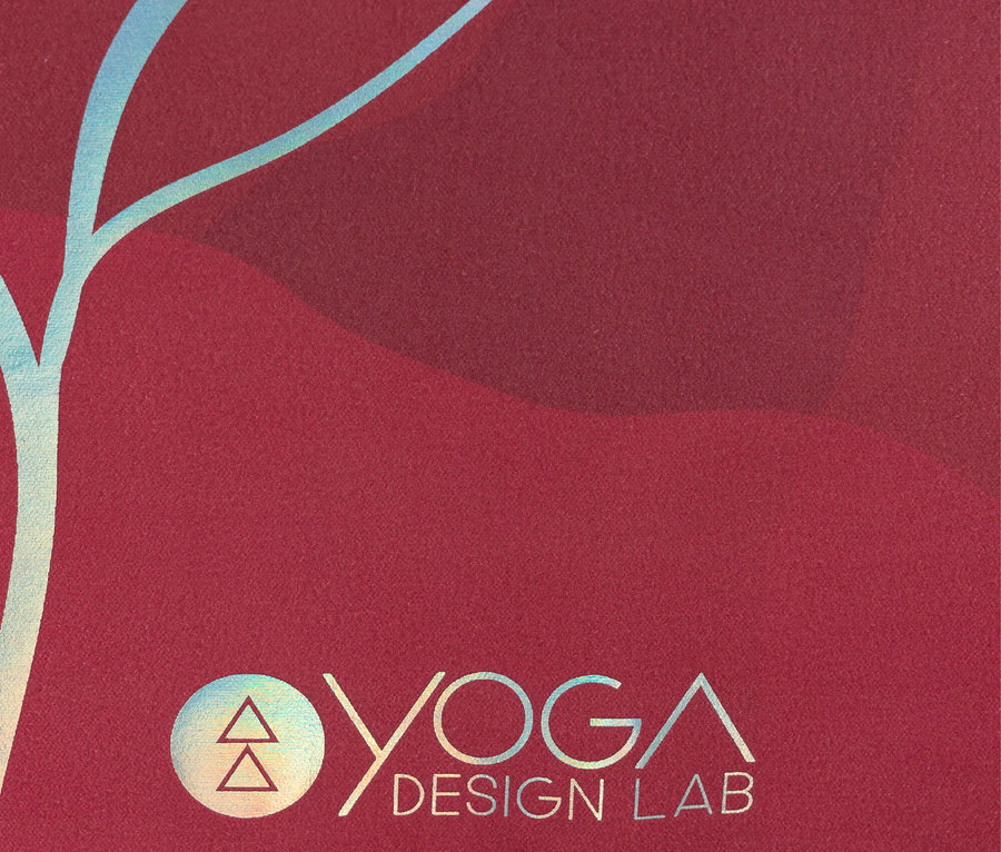 Egy piros jógaszőnyeg részlete, Yoga Design Lab logóval és kék mintával.