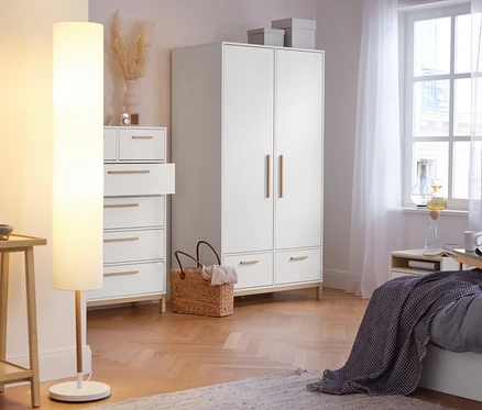 A hálószobában konzolasztal polccal, LED-es állólámpa, textil lámpaernyővel, komód 6 fiókkal, ruhásszekrény és ruhásszekrény fiókokkal »Eklund« látható.