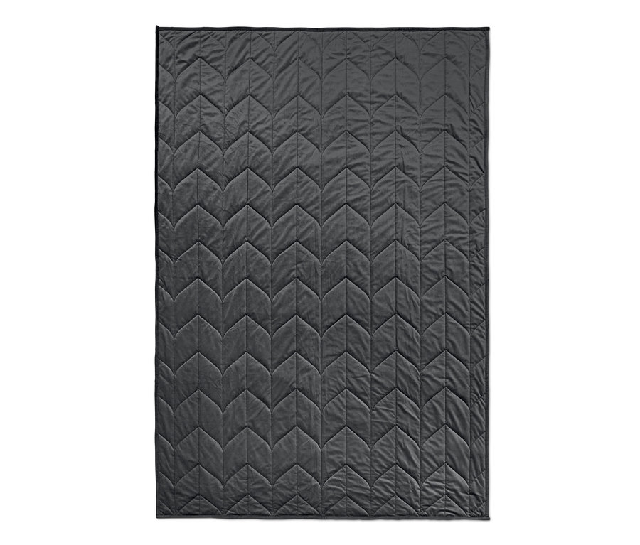 Egy szürke, geometrikus mintázatú, steppelt, lazító hatású súlyozott takaró.