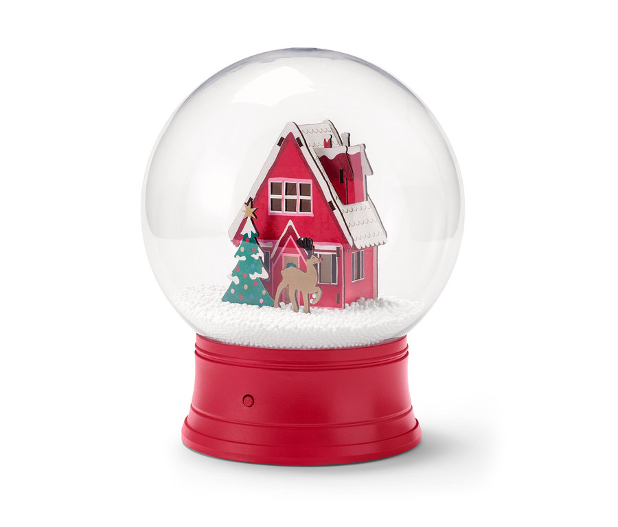 Egy LED-es hógömb belsejében egy piros ház, egy karácsonyfa és egy szarvas figura található.