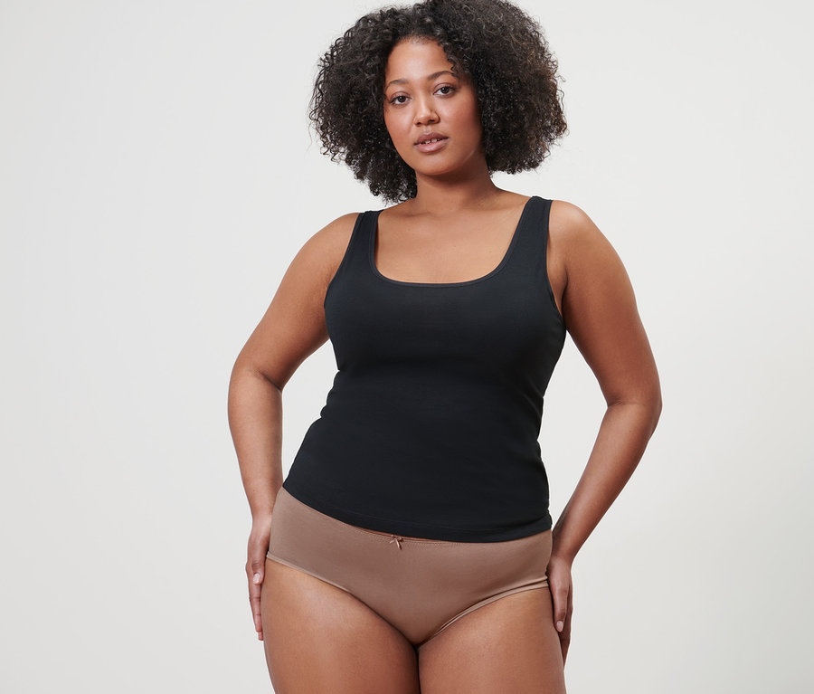 Nő pózol fekete trikóban és 4 francia fazonú alsóban.